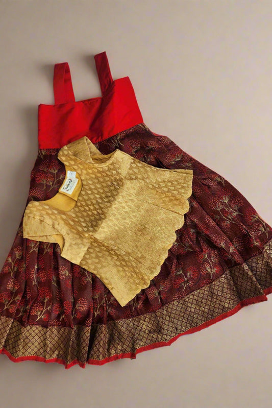 Maroon banaras lehenga with gold border and a gold cut work blouse with cap sleeves, shoulder straps, and a back-open design, displayed on a mannequin.