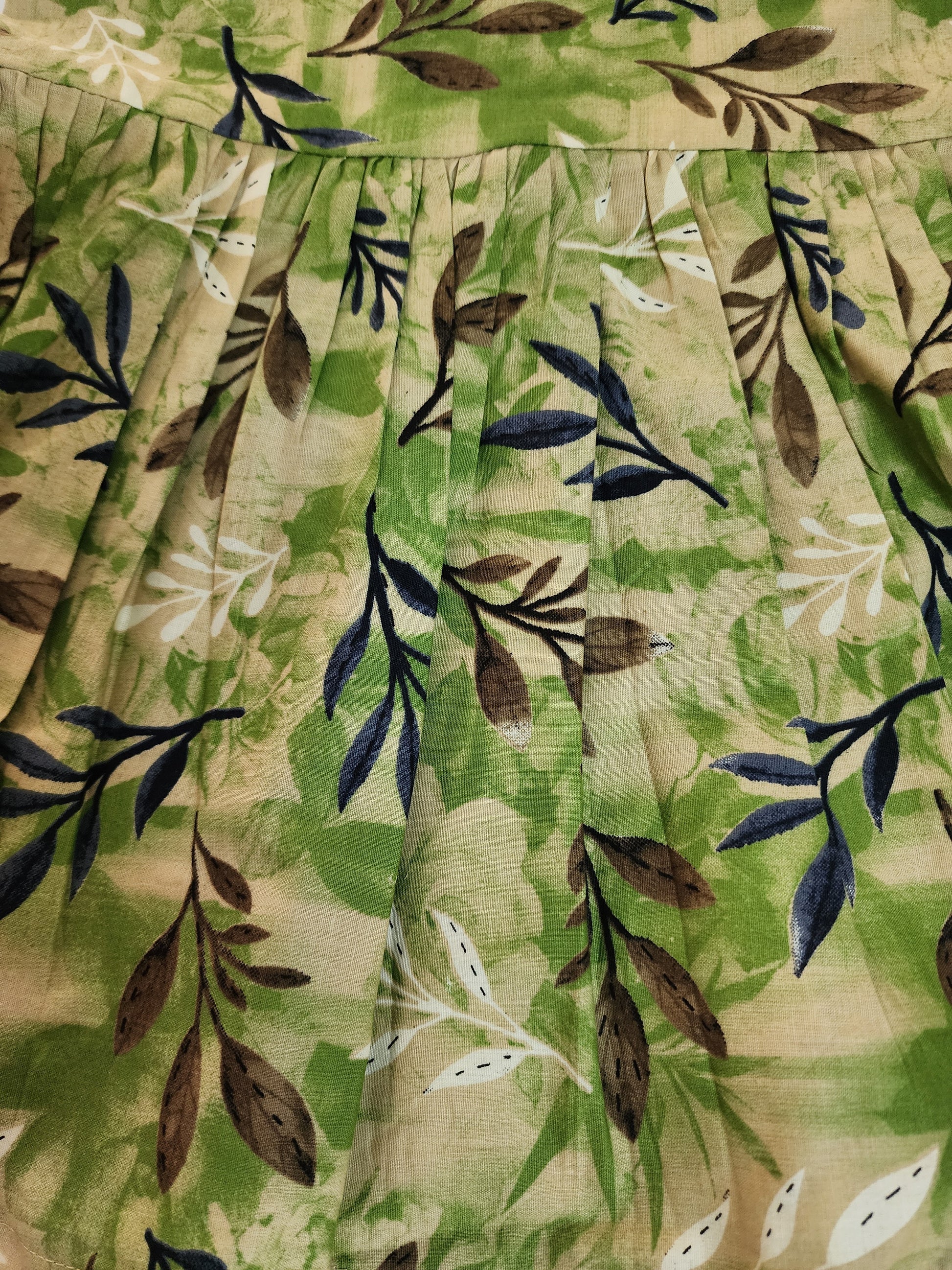 Close-up of a fabric with a leaf pattern on a green and beige background