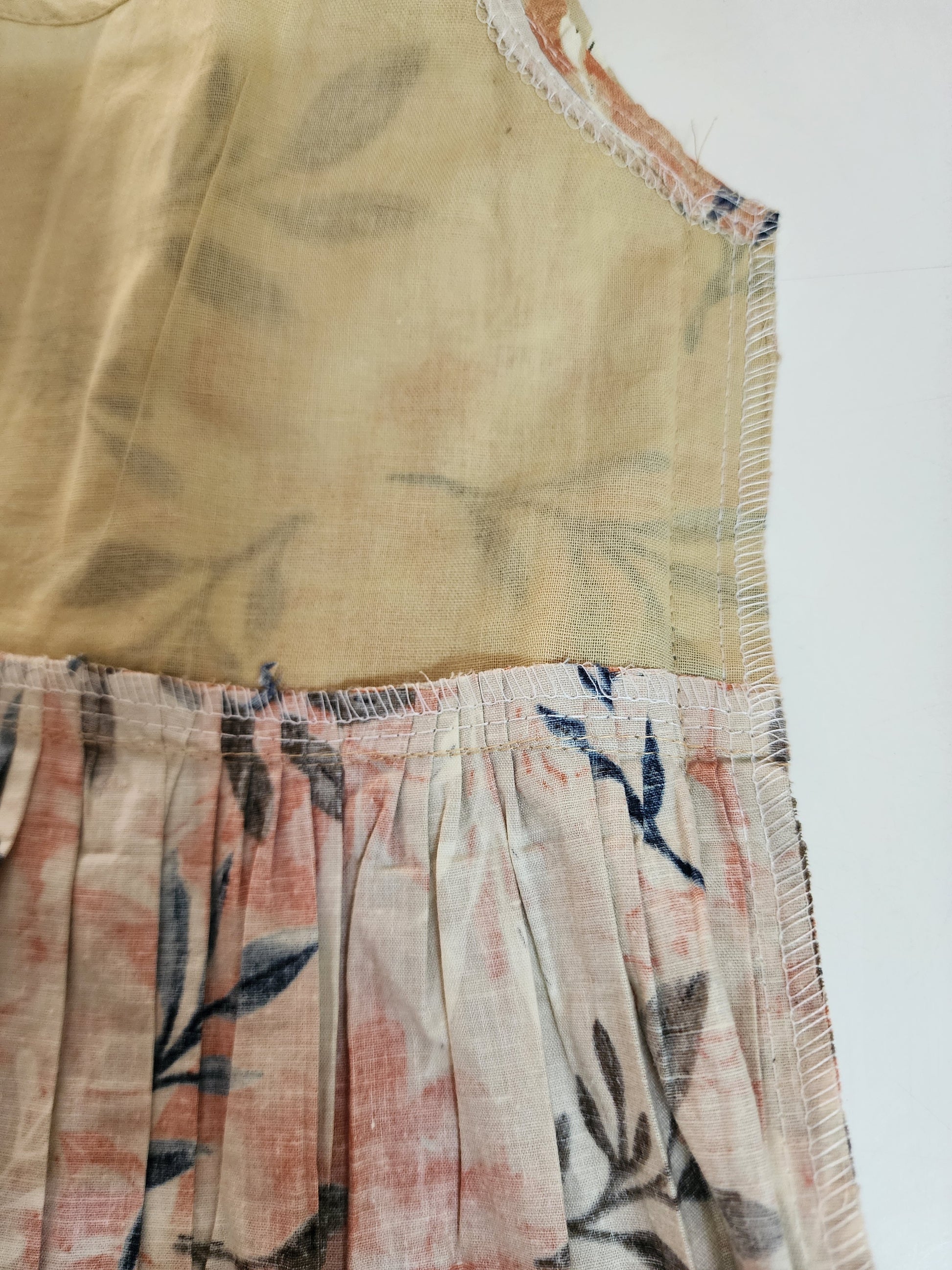 Partial view of a sleeveless top with floral pattern on a plain background