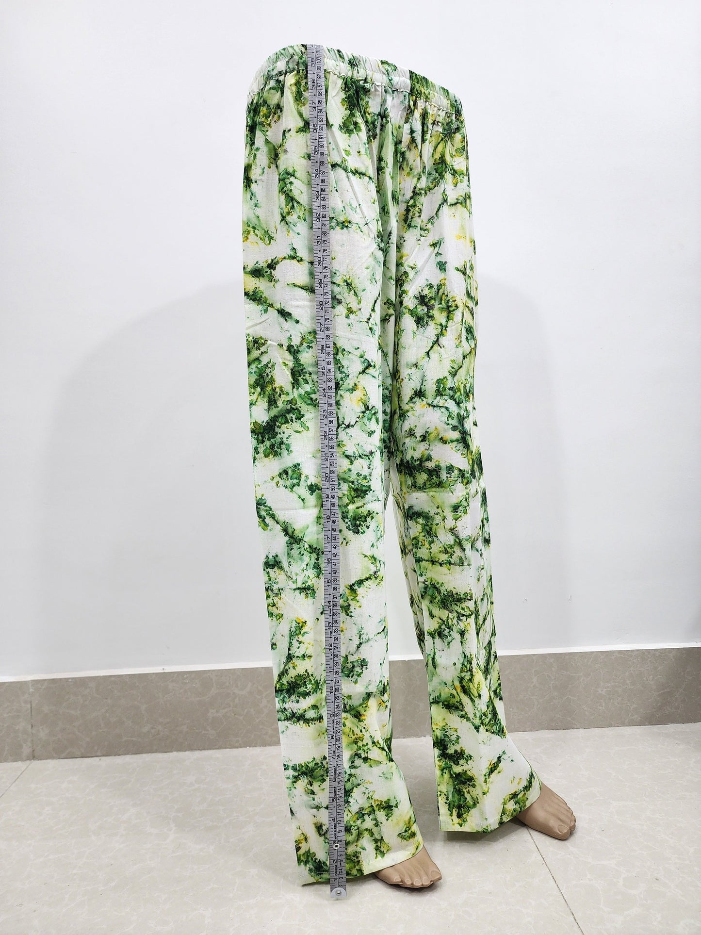 Green and white patterned pants with a measuring tape on a white background
