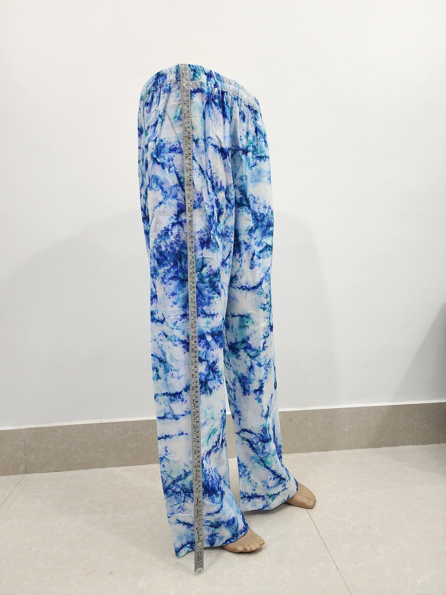 Blue tie-dye pants with a measuring tape on a white background