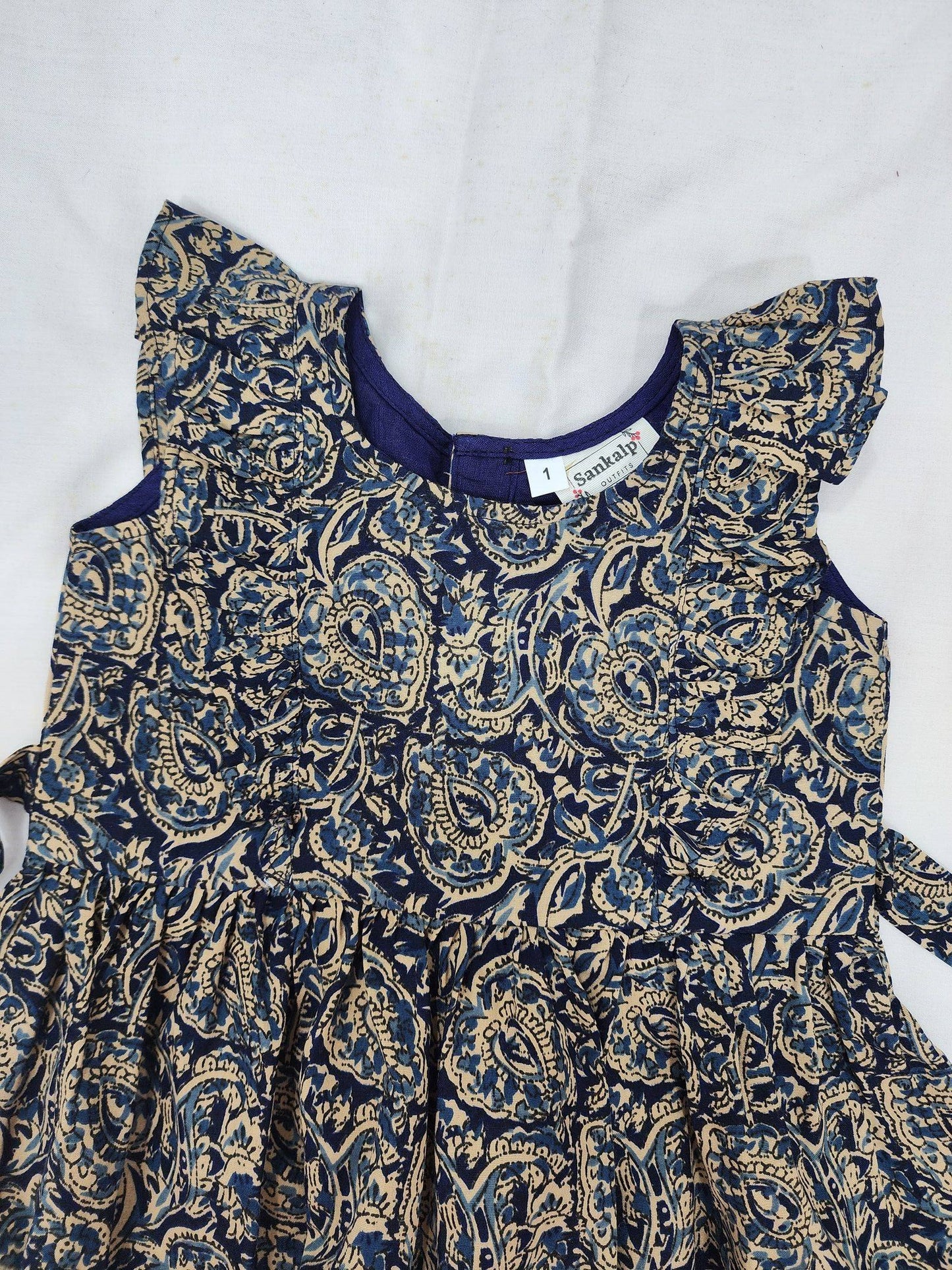 Children's dress with blue and gold paisley pattern on a white background